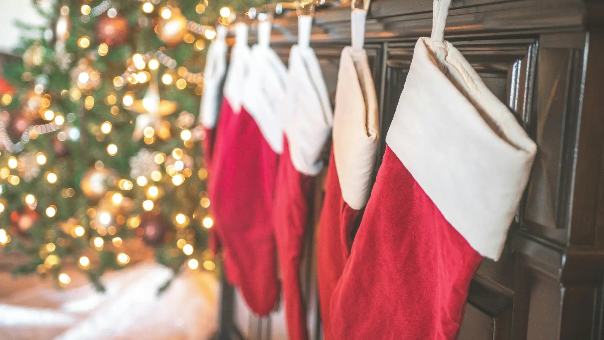 Red and white christmas stocking with fur trim, hanging on a fireplace mantel.