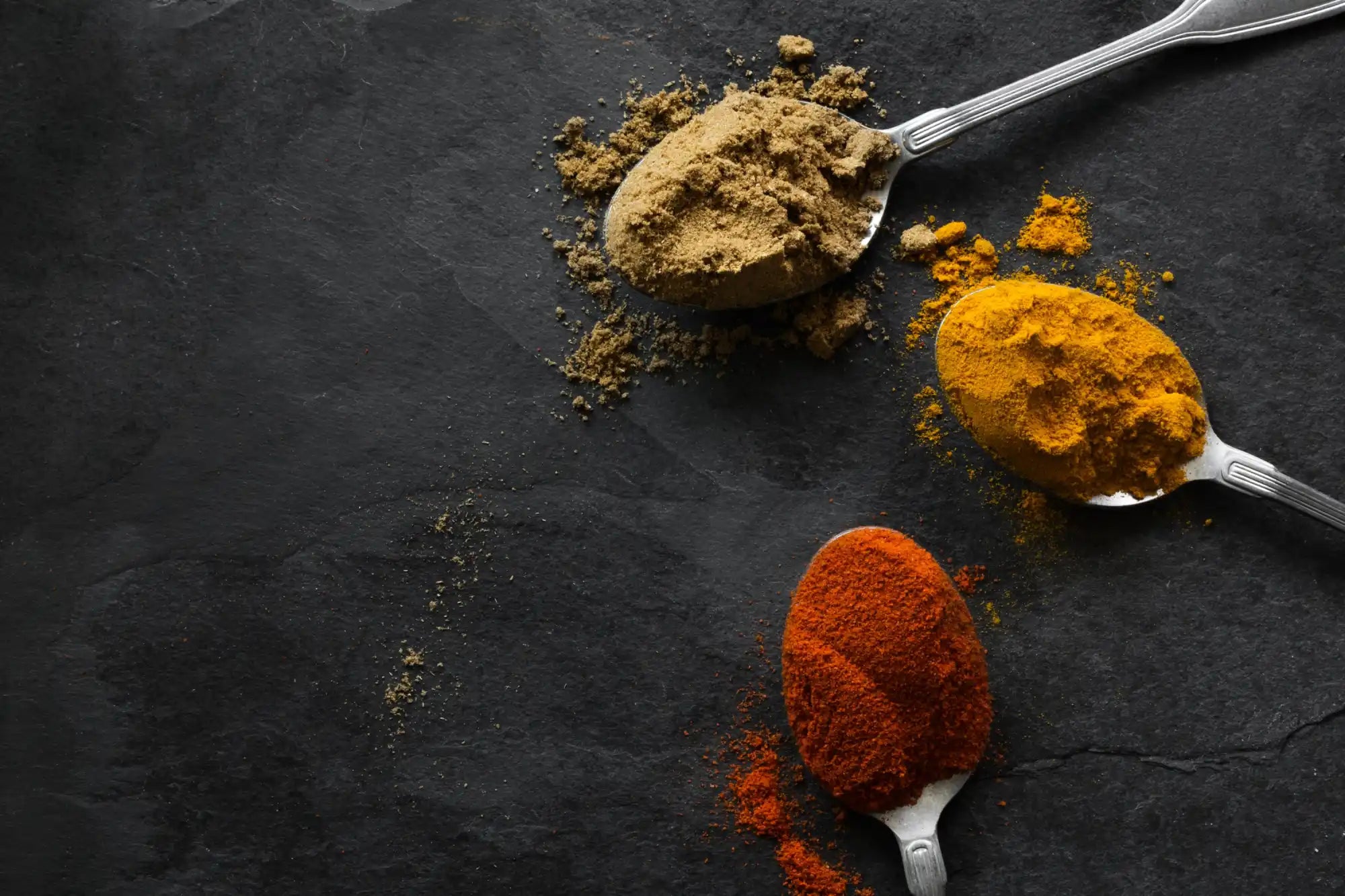 Three spoons of various colorful spices.